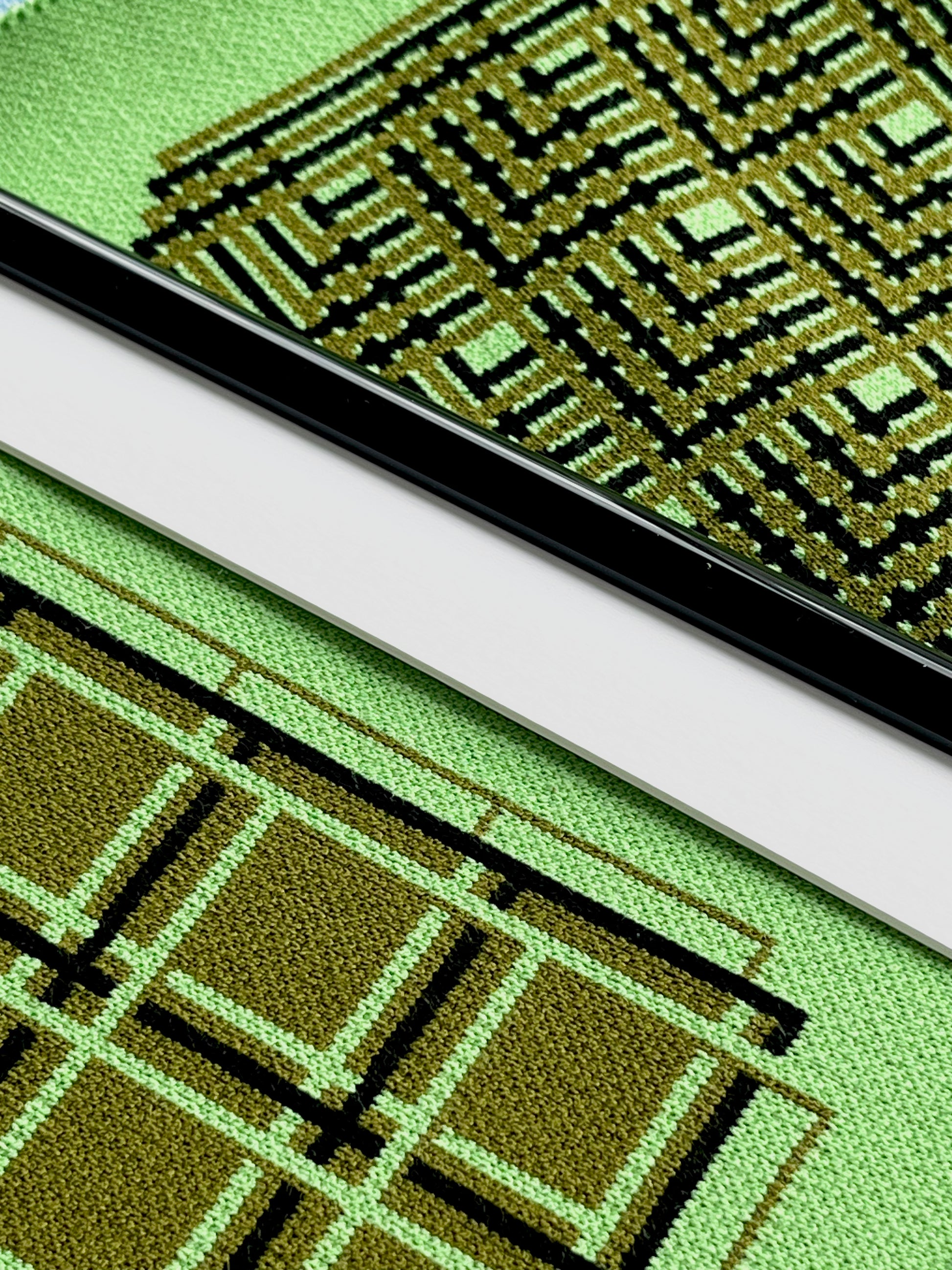 Close-up of a green fabric with geometric pattern and a black border.