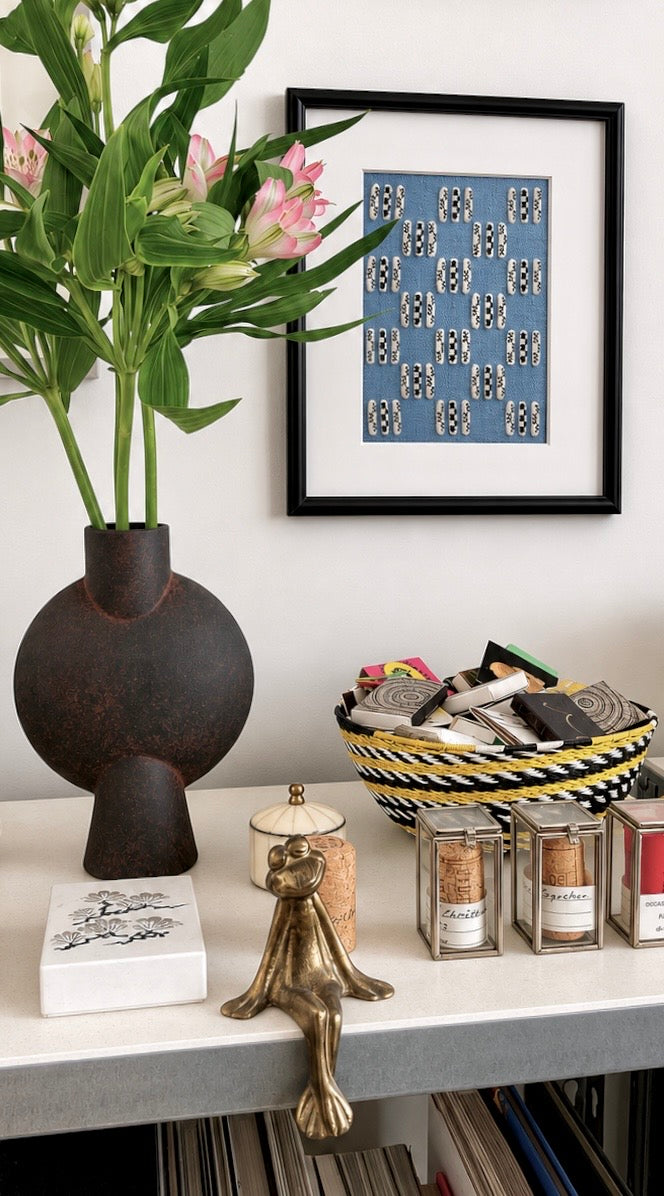 Decorative shelf with a vase, flowers, framed artwork, and various small items.