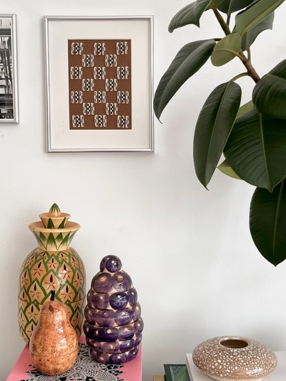 Decorative vases on a table with a framed artwork and plant in the background