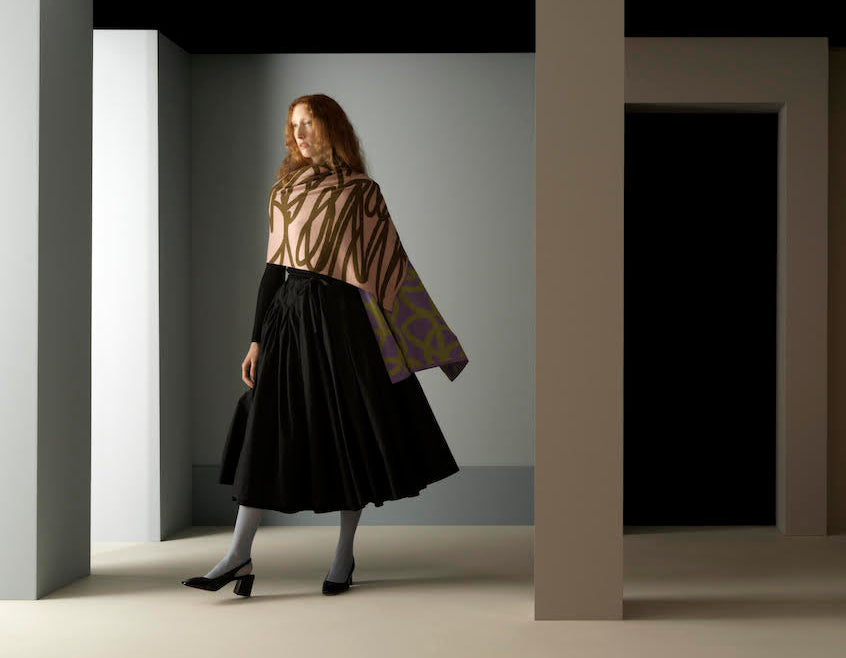 Woman in a stylish outfit standing in a minimalistic room with geometric shapes.