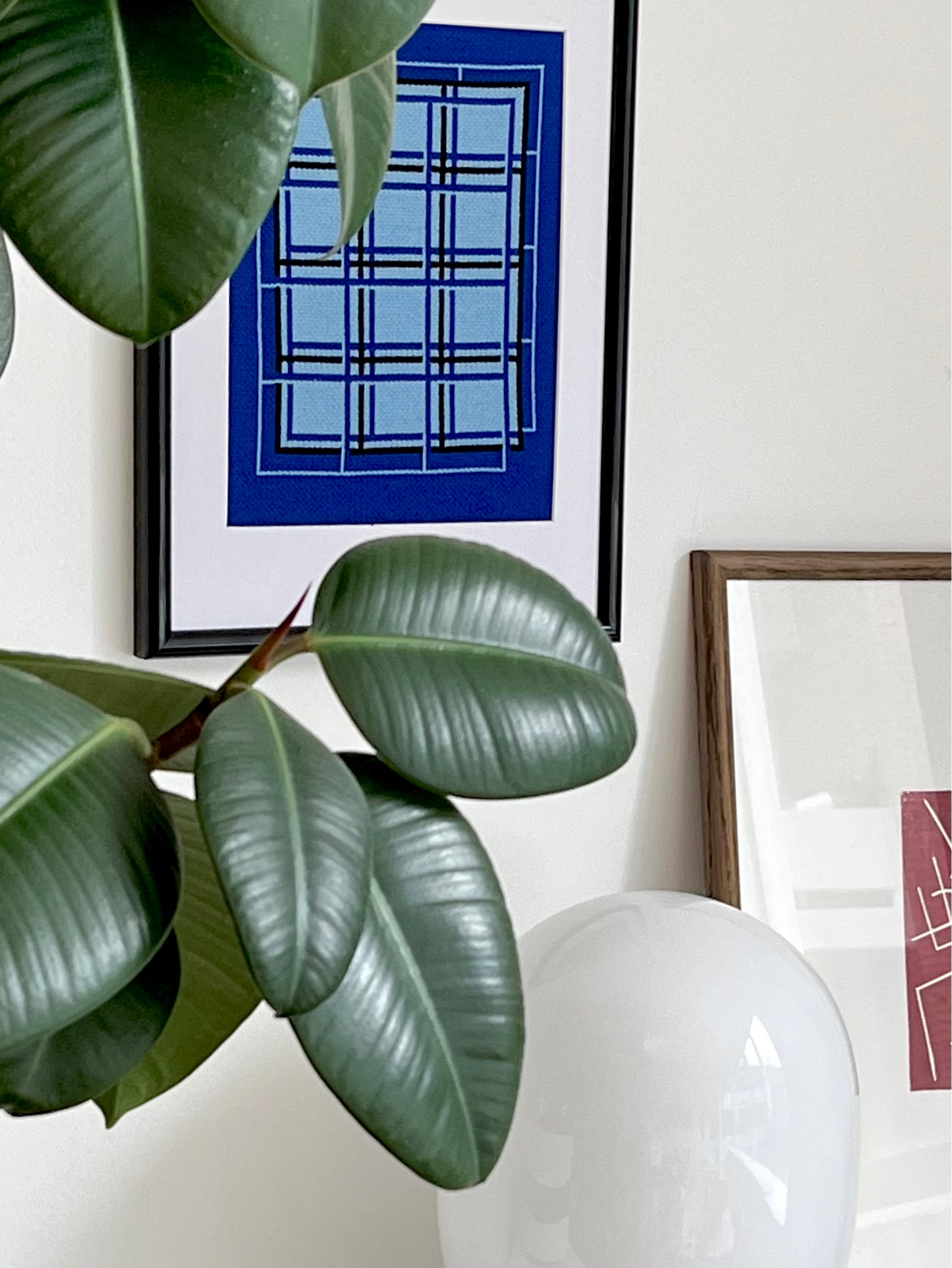 Indoor plant on a shelf with decorative items and framed art in the background